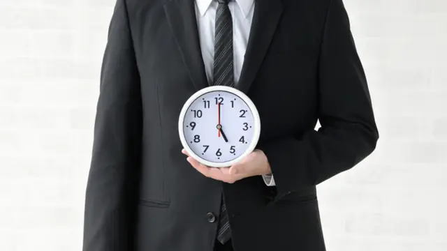 Trabalhador segurando relógio, simbolizando horas extras